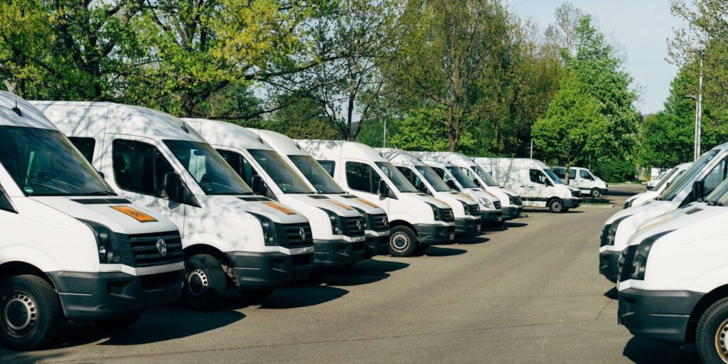 White commercial vehicles parked in two straight lines facing each other.